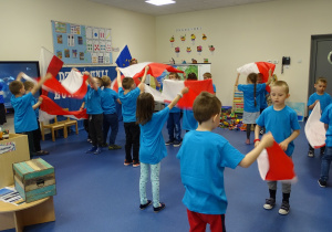 Dzieci tańczą z flagami przy piosence